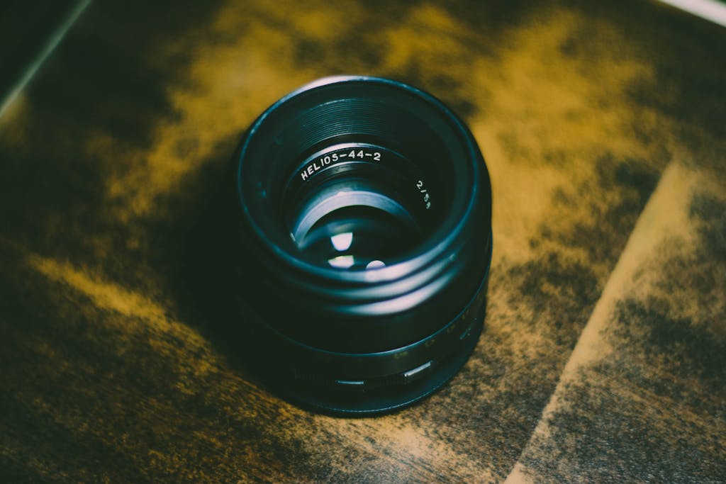 Detailed view of a camera lens on wood background, highlighting its vintage design.